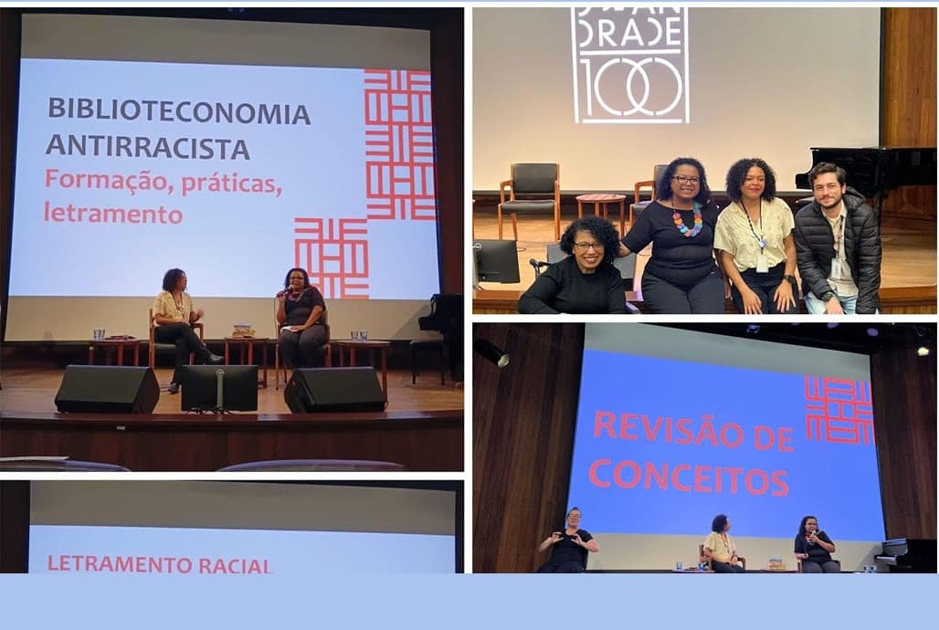 Palestrantes no palco diante do telão "Biblioteconomia antirracista: formação, práticas, letramento"