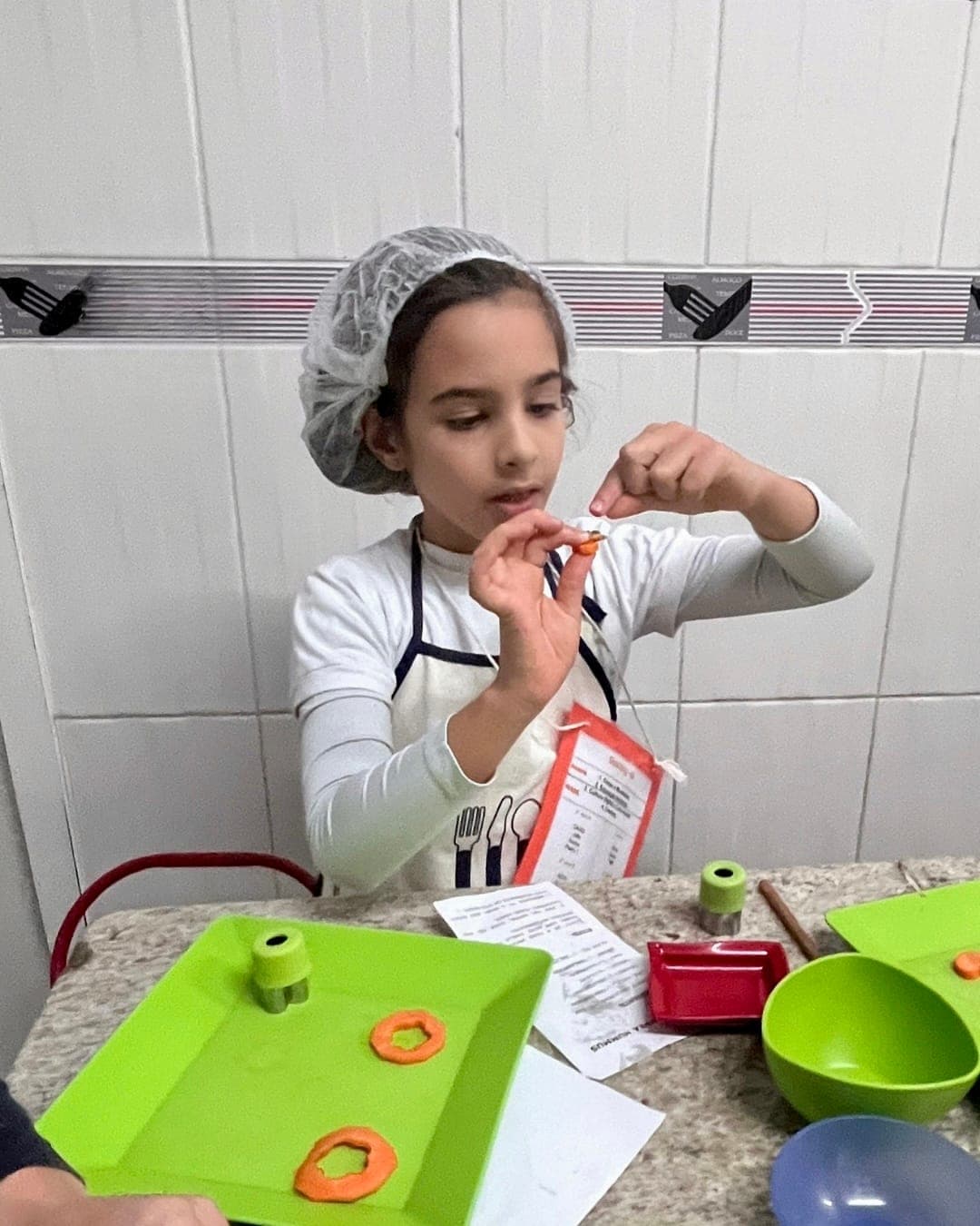 Aluna de touca mostra uma forma de cenoura feita com o cortador de legumes