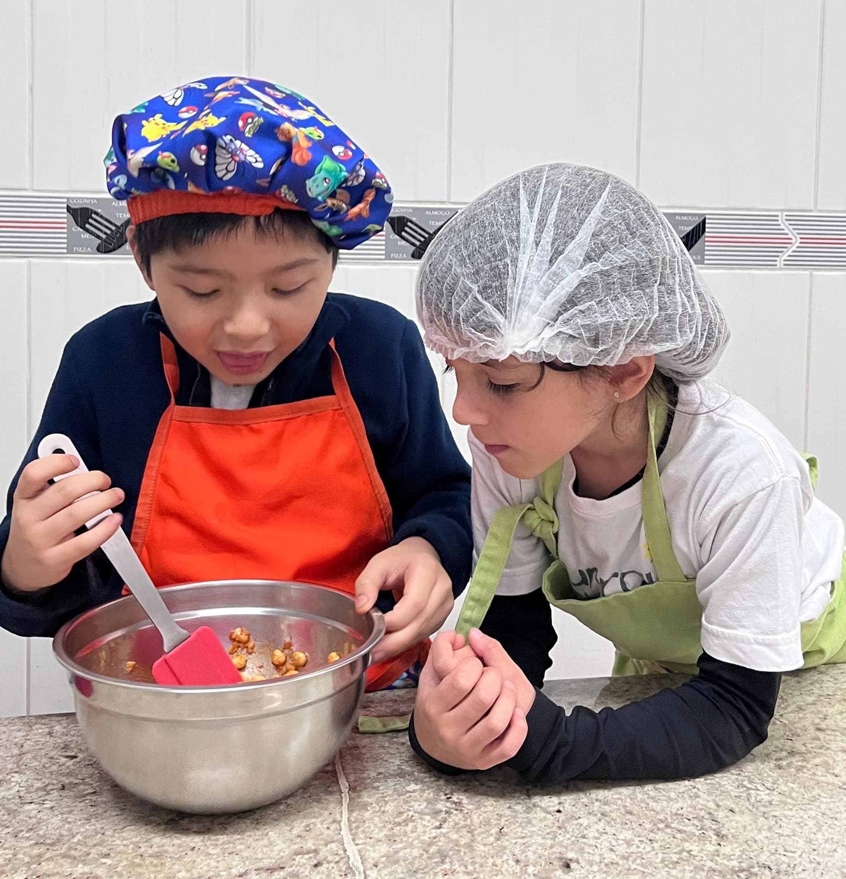 Dois meninos misturam o grão-de-bico temperado com uma espátula vermelha