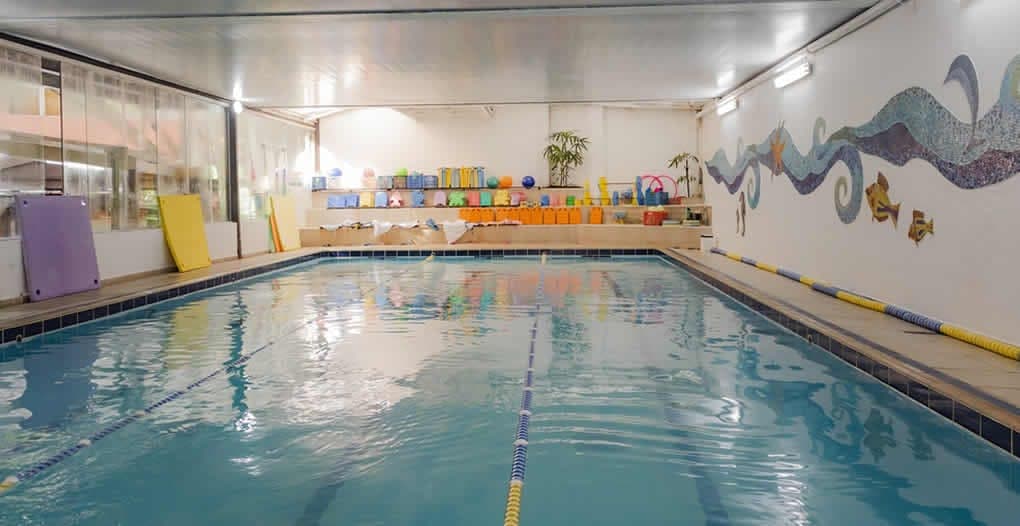Piscina coberta da escola com raias, pranchas e materiais de aula de natação