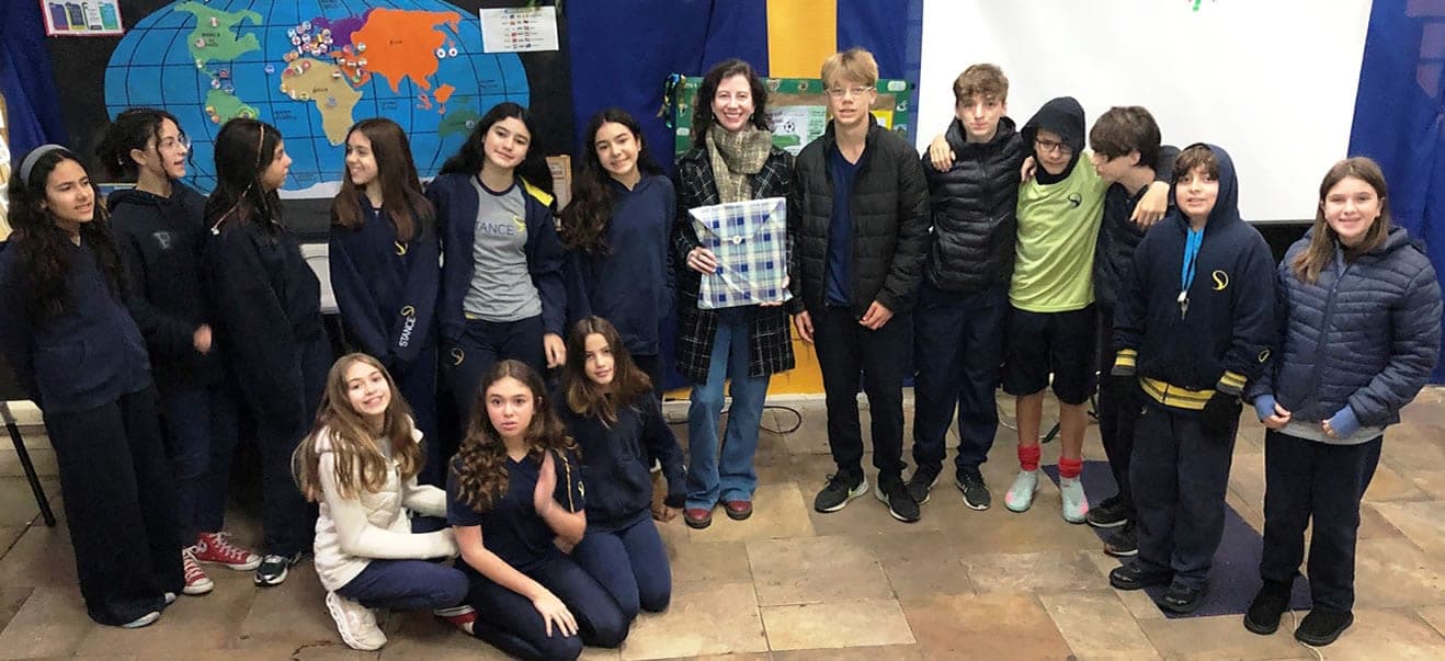 Elisa Martins com os alunos do 7º ano diante de um mapa-múndi após o encontro