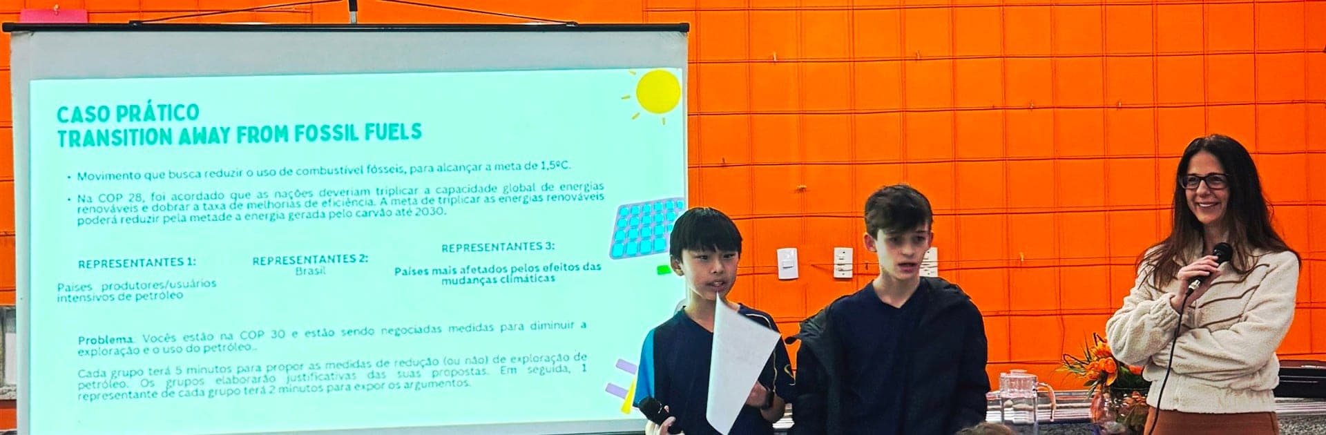 Alunos apresentam o caso prático sobre a COP 30 e a transição dos combustíveis fósseis ao lado de Maria Cristina Gueorguiev