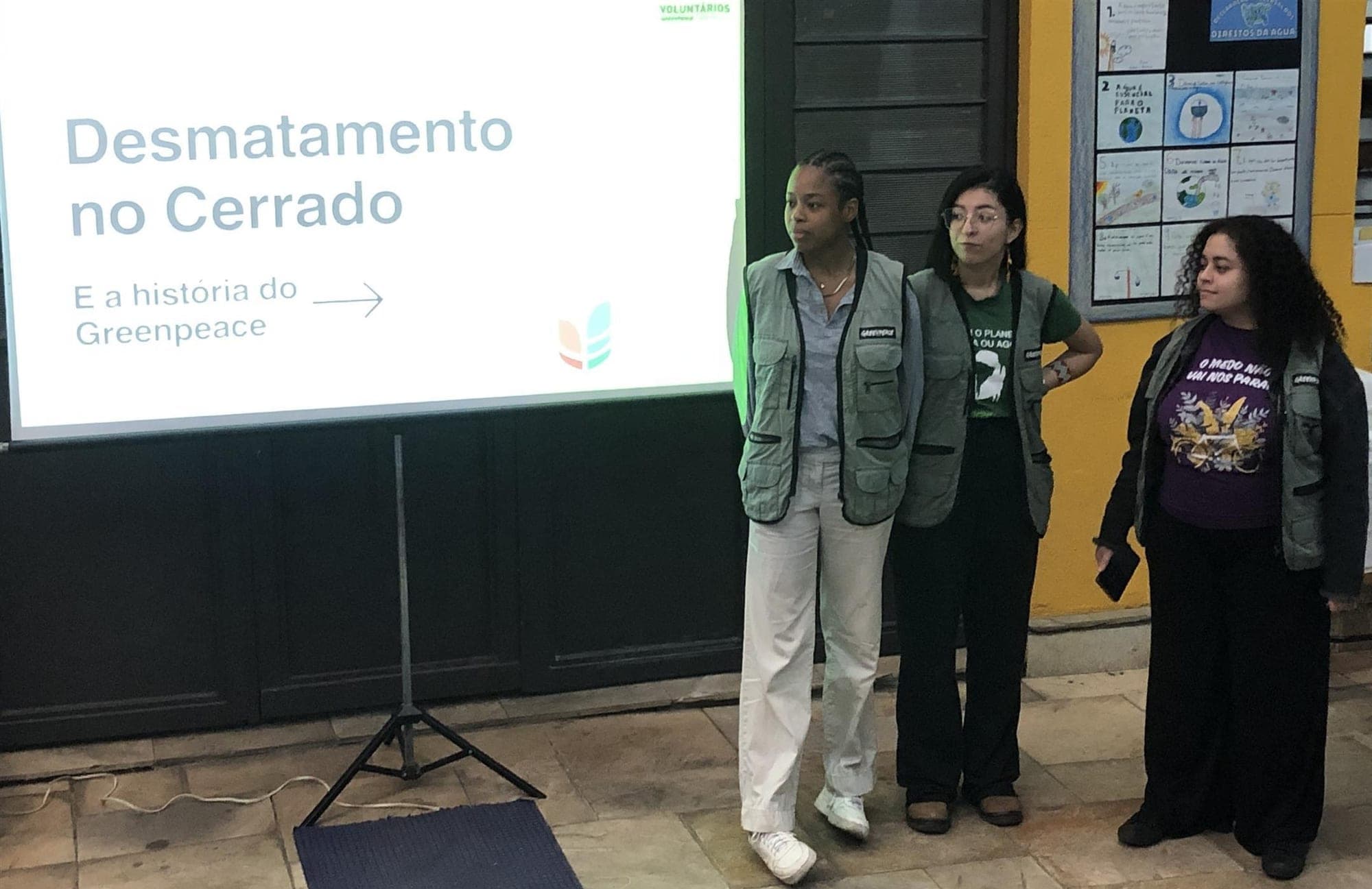 Voluntárias do Greenpeace ao lado da projeção "Desmatamento no Cerrado e a história do Greenpeace"