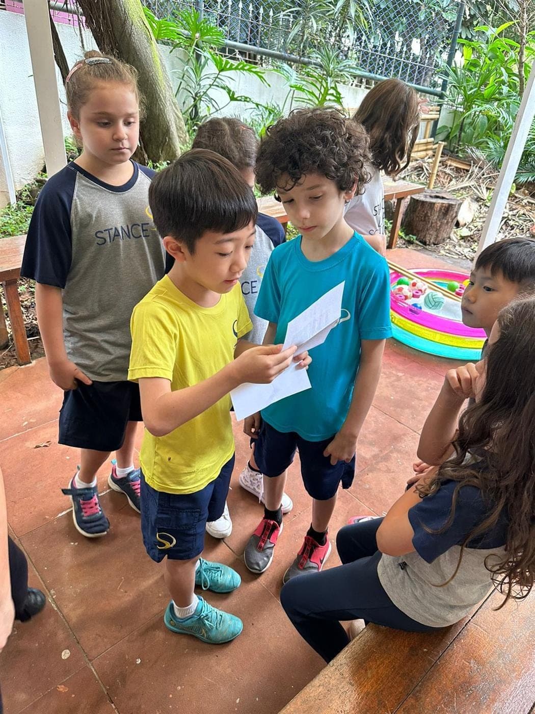 Alunos do 2º e 3º ano leem uma pista da Gincana Sustentável no pátio