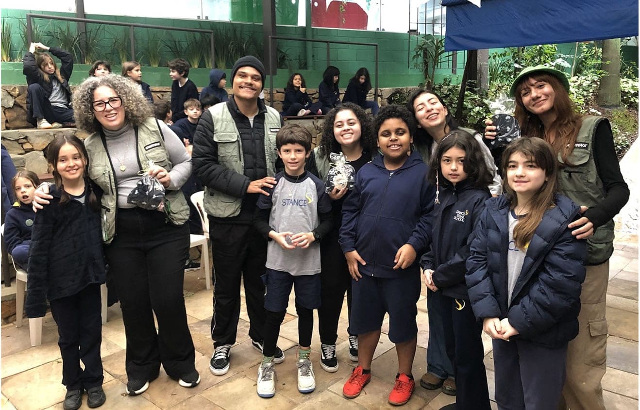 Voluntários do Greenpeace posam com alunos do 3º e 4º ano no pátio da escola
