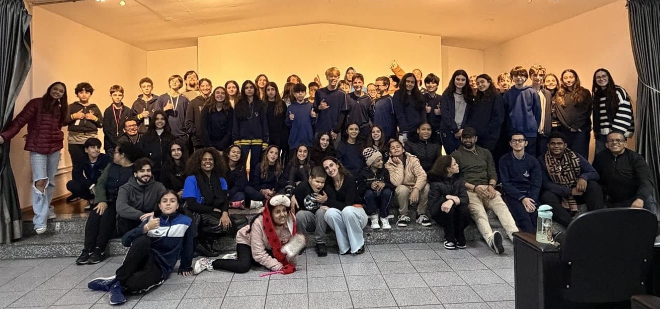 Grupo grande de alunos e educadores reunidos em um auditório da Escola Helen Keller