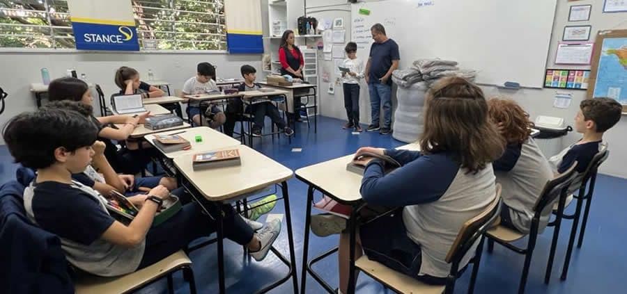 Turma do 5º ano em sala acompanha a entrega dos cobertores arrecadados a representante de instituição