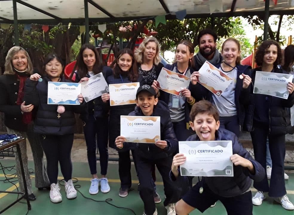 Alunos premiados no Canguru exibem certificados e medalhas ao lado de professores na cerimônia na escola