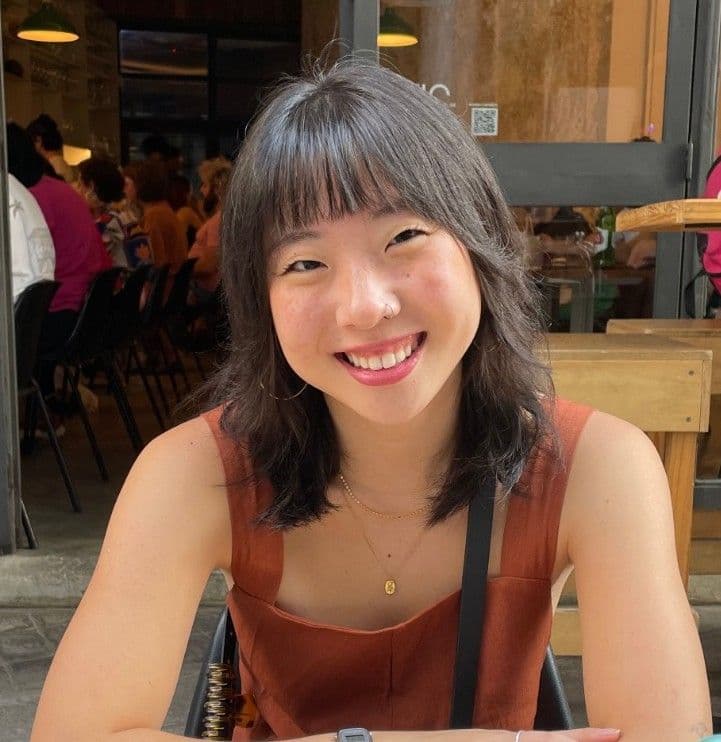 Retrato de Stephany Lee sorrindo, sentada em uma mesa ao ar livre