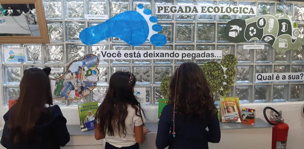 Alunas diante do painel "Pegada ecológica: você está deixando pegadas... Qual é a sua?"