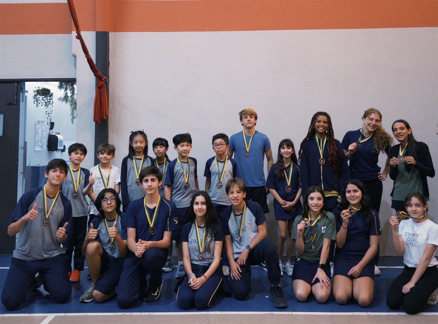 Grupo de alunos com medalhas de bronze do Canguru de Matemática posa na quadra da escola