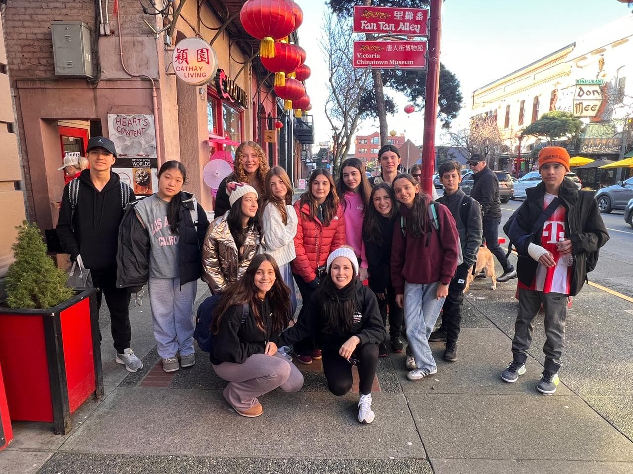 Alunos e professora posam em uma calçada da Chinatown de Victoria, junto à placa Fan Tan Alley